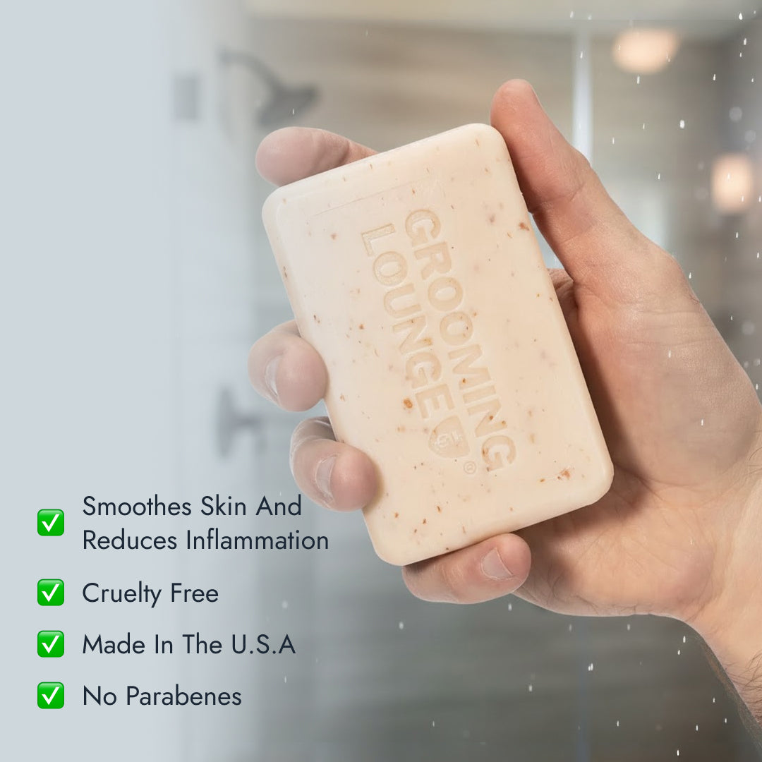 Hand holding a bar of soap with 'Grooming Lounge' branding, set against a blurred shower background.